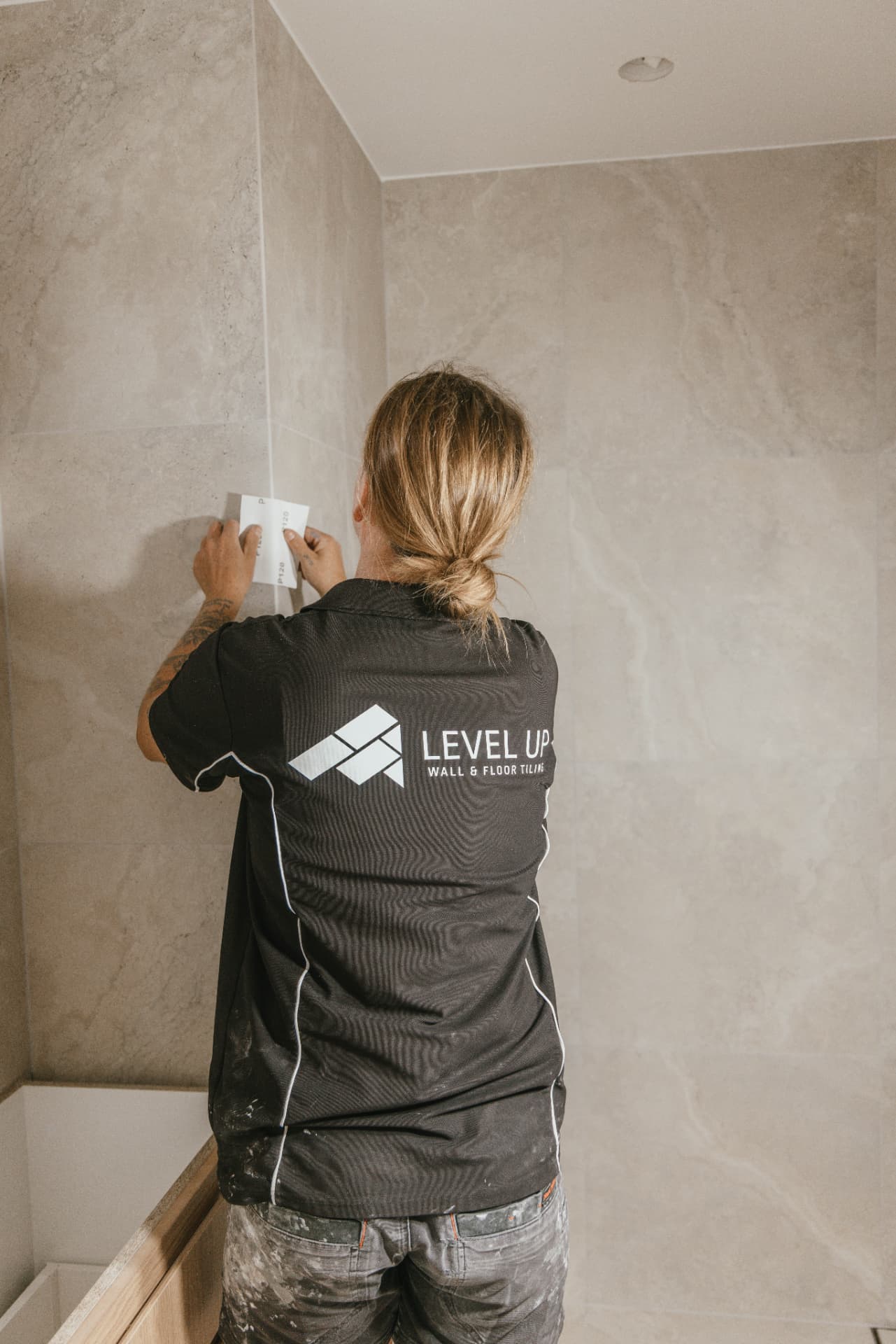 Sarah grouting a tiled wall on site