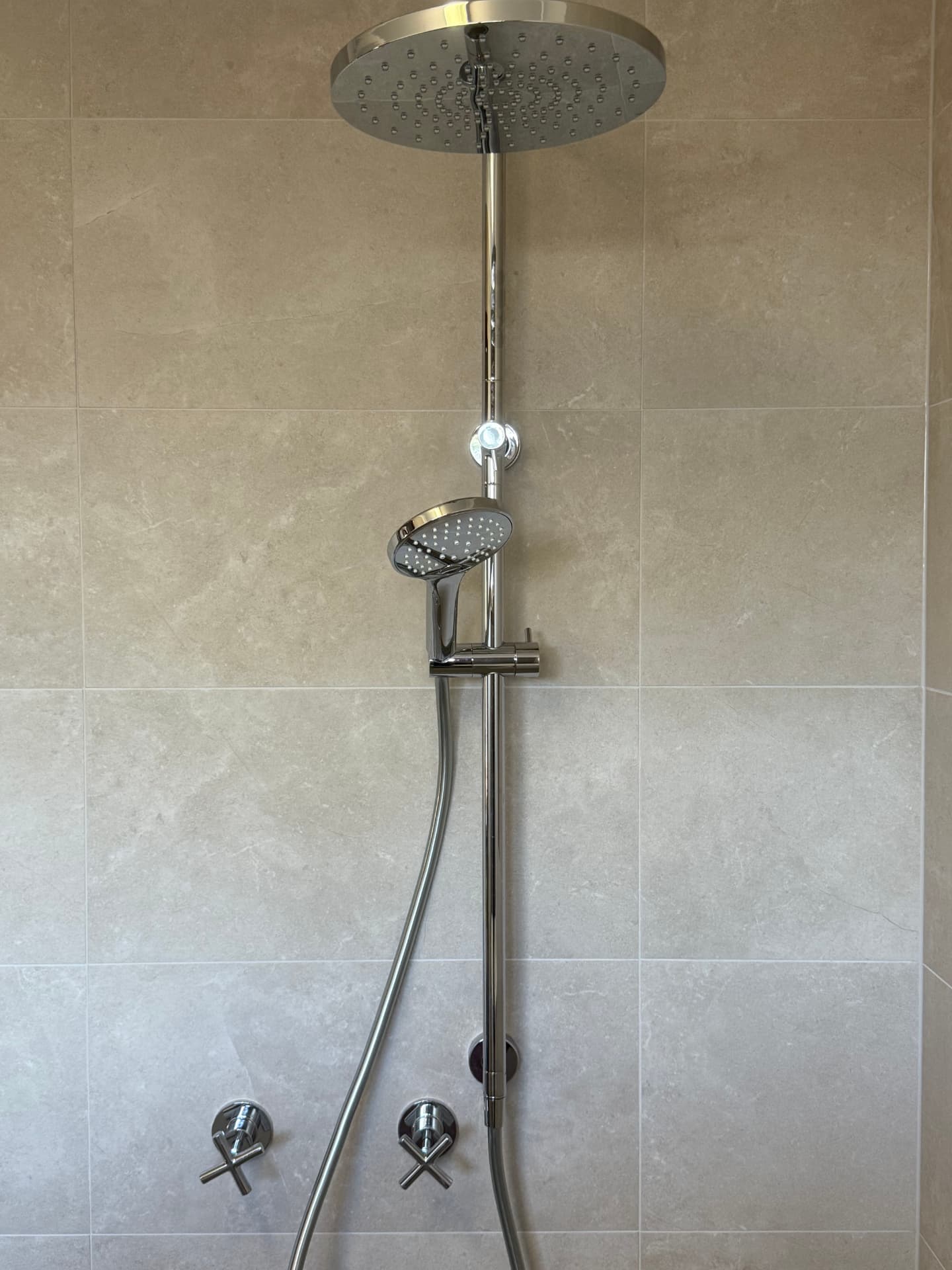 Neutral tiled shower with the floor falling to the waste