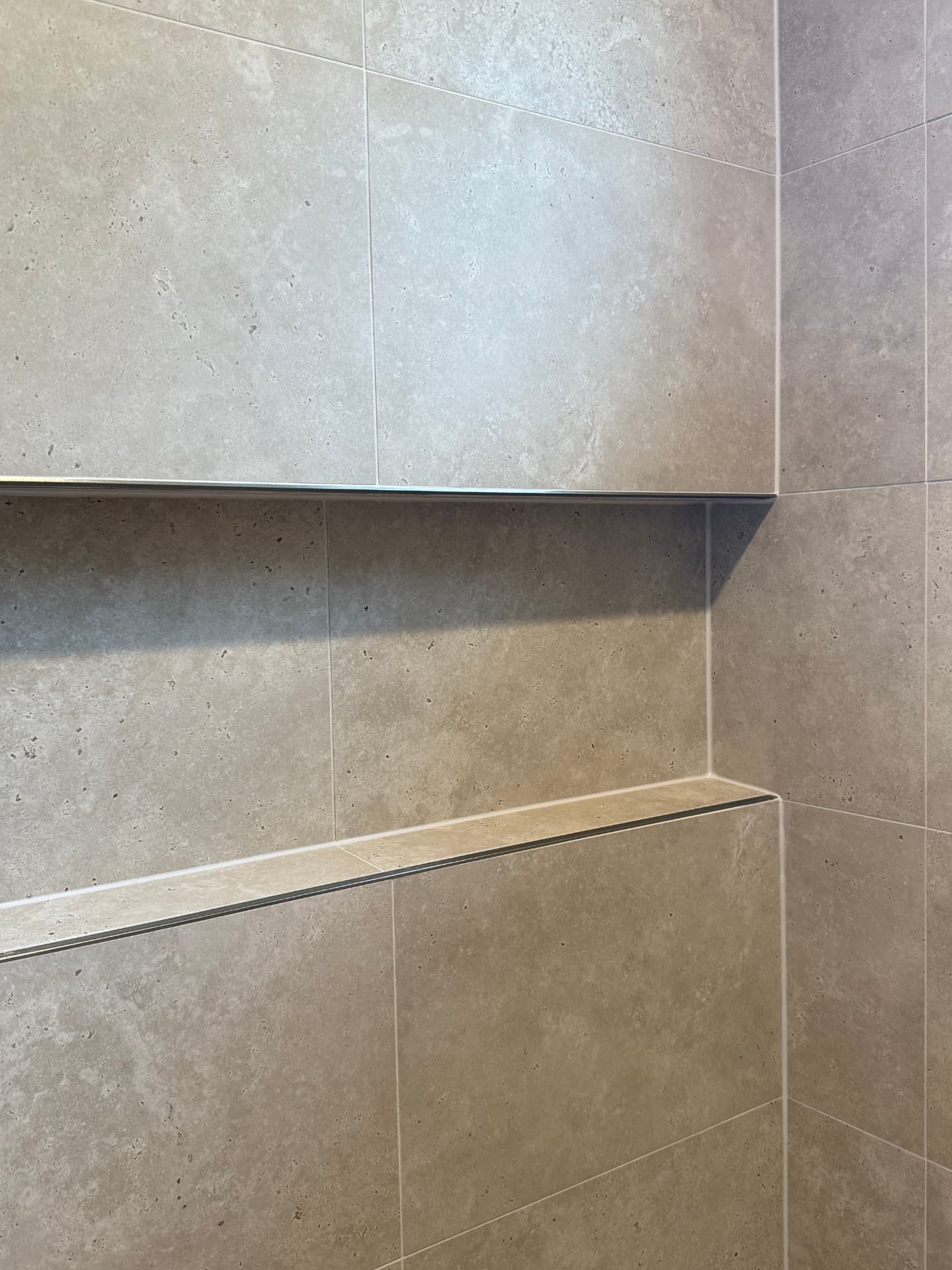 Close-up of a tiled shelf edge finished with metal trim
