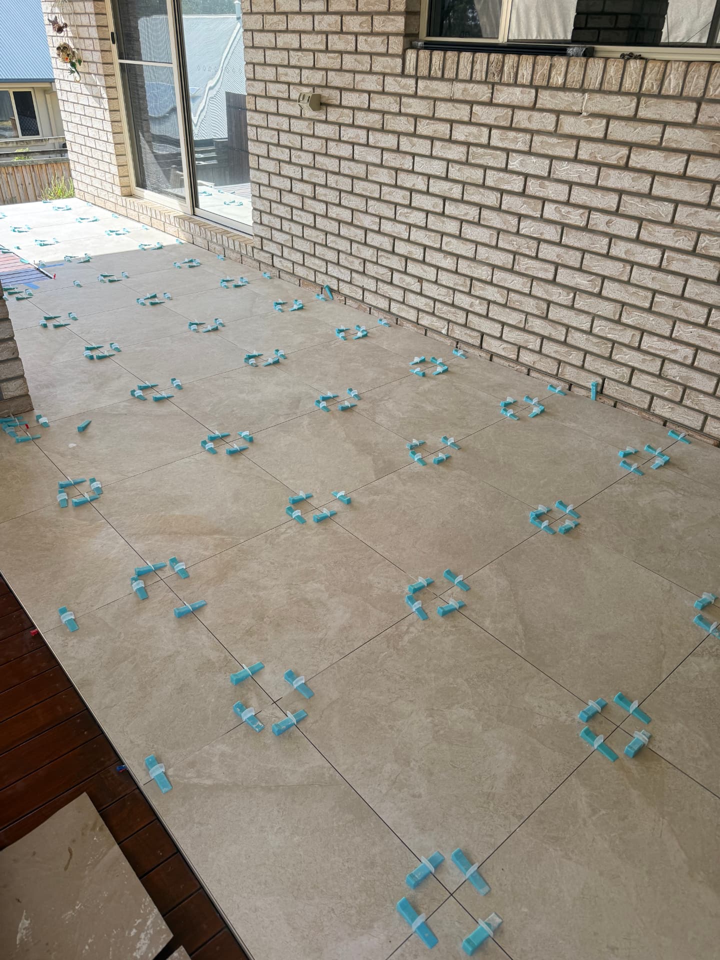 Large-format outdoor floor tiling in progress with levelling clips between tiles